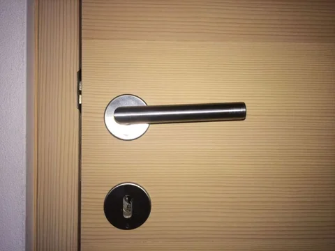 Maniglia in acciaio inox 90° su porta in abete sbiancato